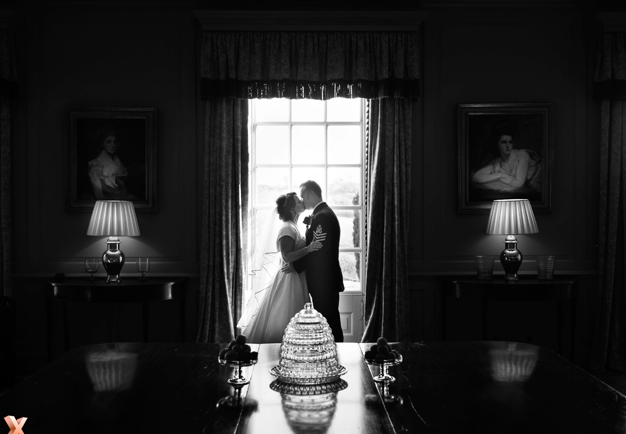 Couple kiss silhouetted in front of a window
