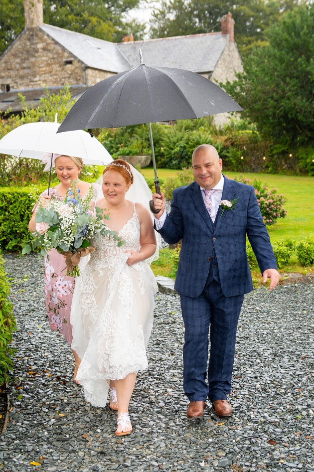 Bride's father holds umbrella