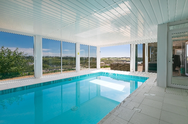 indoor pool with panoramic windows looking out to hillside and coasts