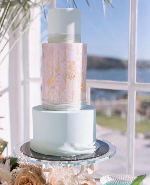 Three tier modern wedding cake in front of window with coastal view