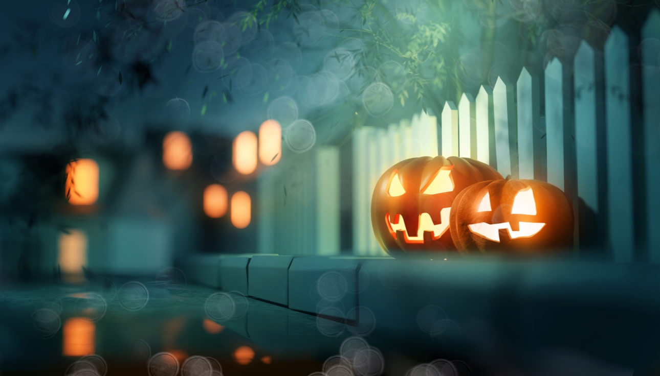 Carved Halloween pumpkins against a white picket fence