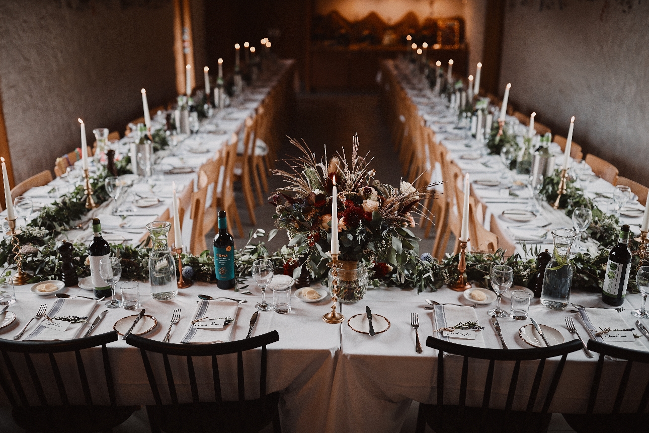 long trestle tables decorate for wedding in a barn