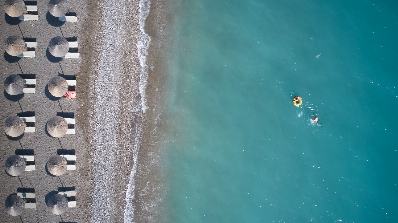 beach with two rows of parasols and lounges then into blue sea