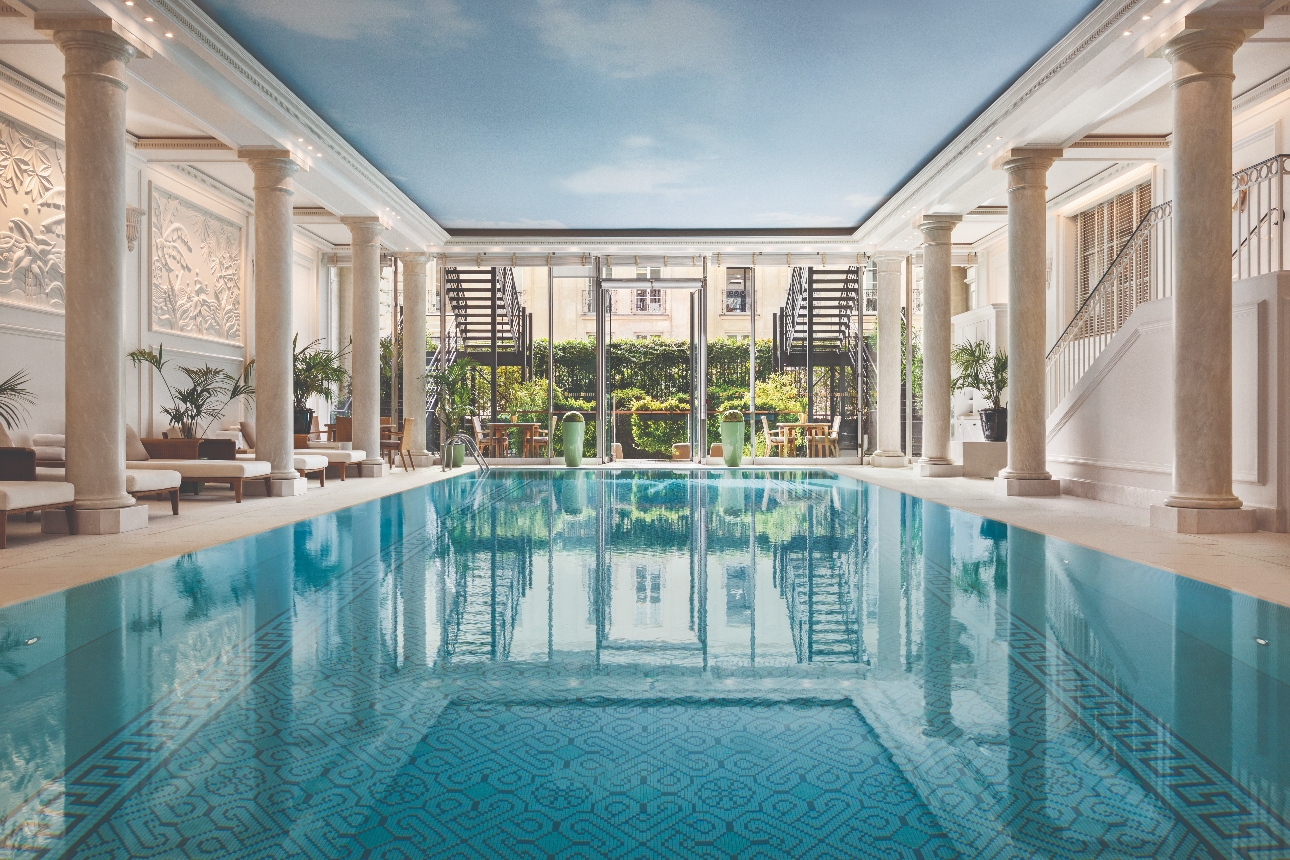 large pool, roman style marble pillars, loungers by the sides 