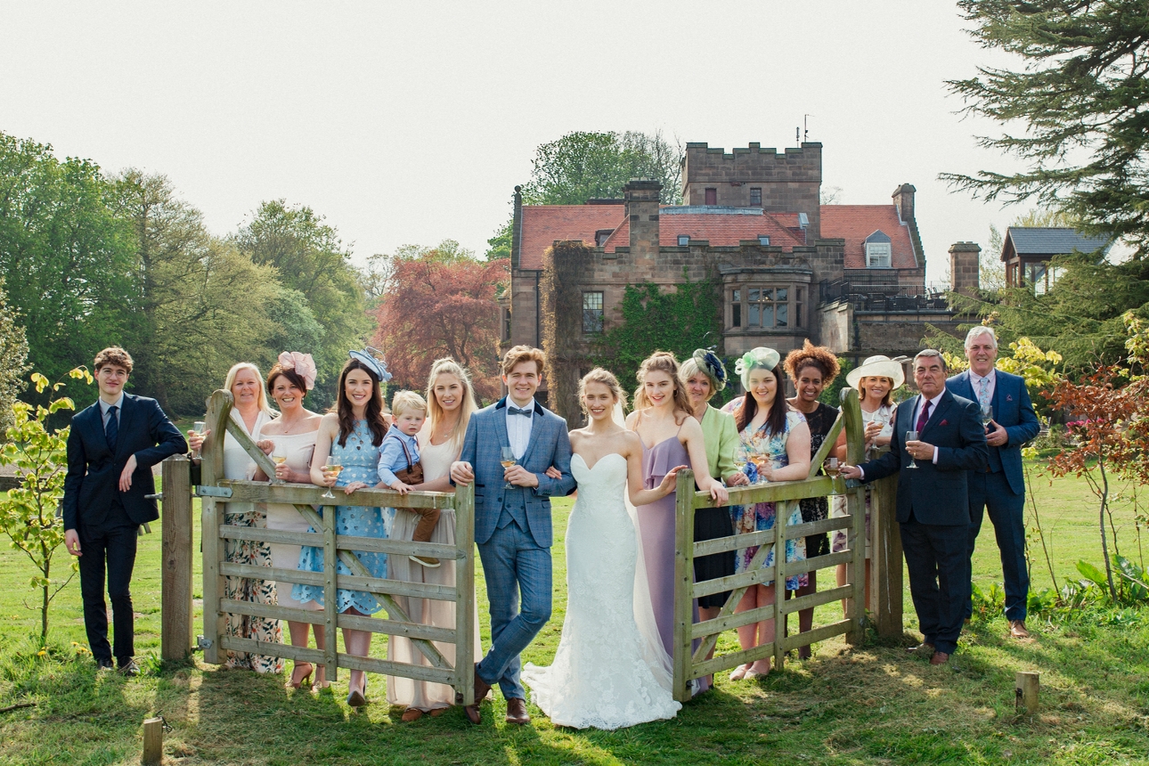 wedding couple and guests in field standing in front of manor house