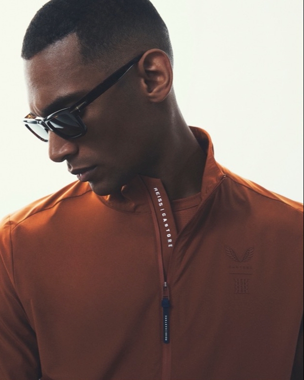 A man wearing glasses and an orange jumper