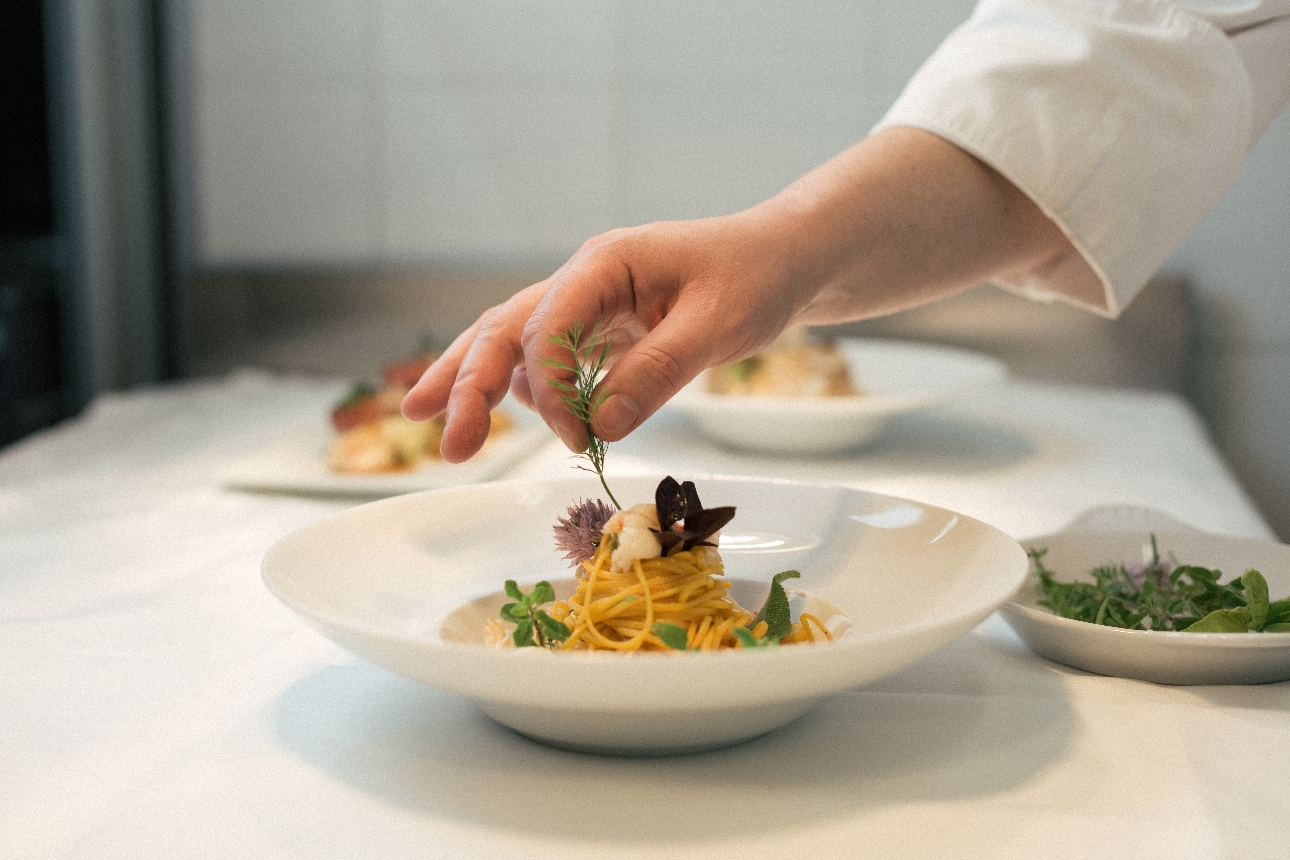 chef putting garnish on a dish of spaghetti