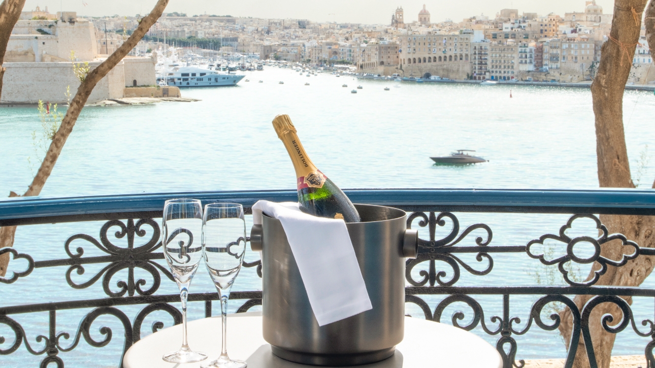 bottle of champagne in ice bucket, placed on table overlooking a harbour