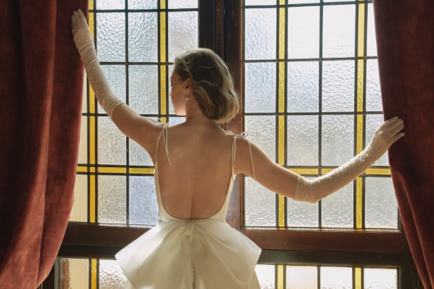 woman in wedding dress stood in front of window