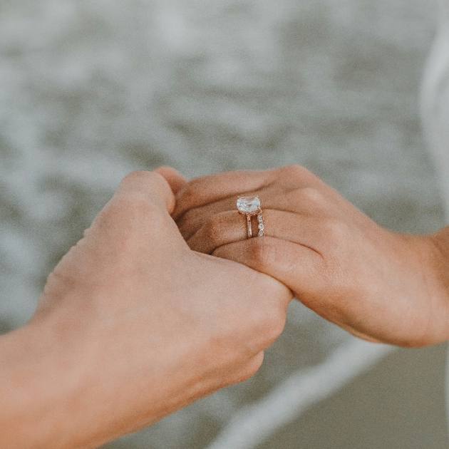 two people holding hands. One person with two rings stacked on one finger 