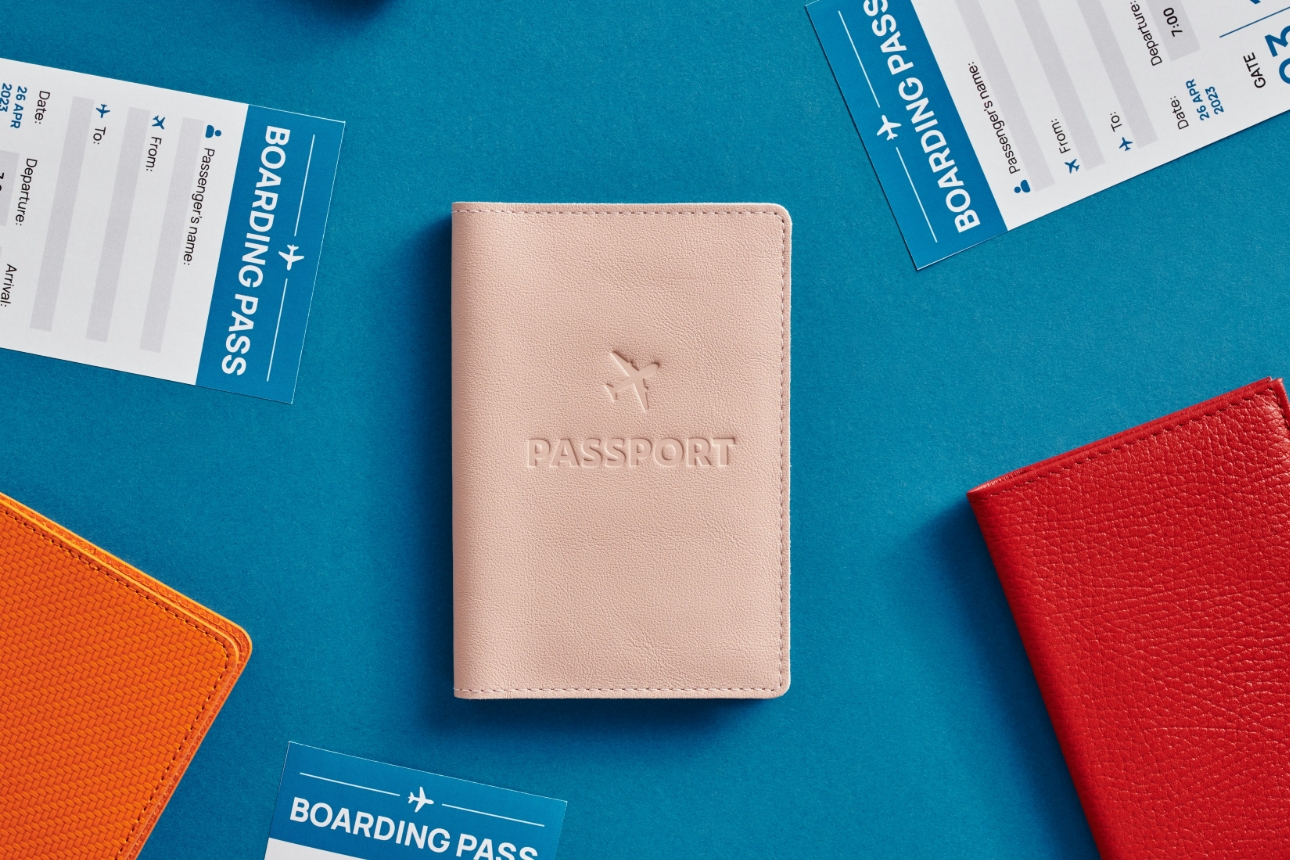 pink passport cover on blue table with plane tickets scattered around it