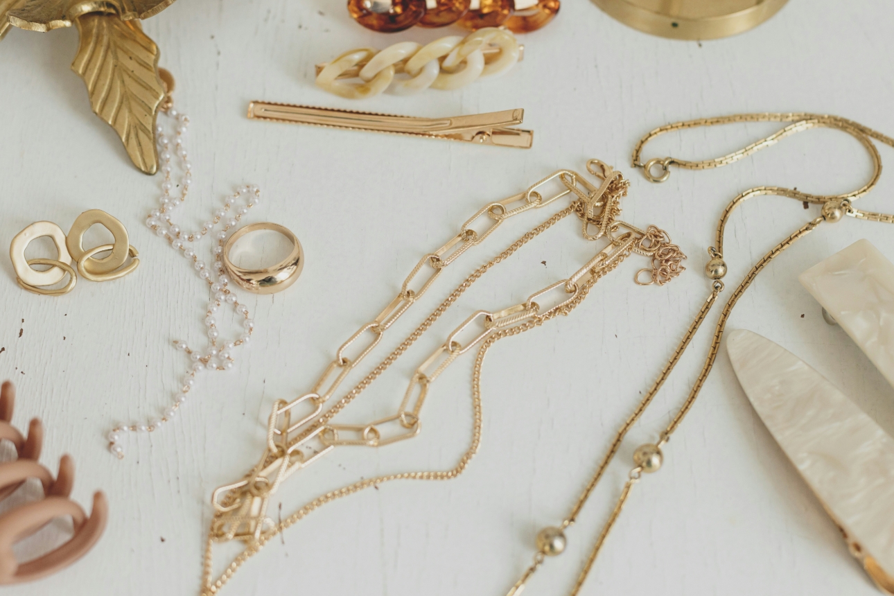 collection of gold jewellery scattered on white wooden table